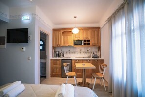 Una habitación de hotel con cama, kitchenette, televisión y baño.