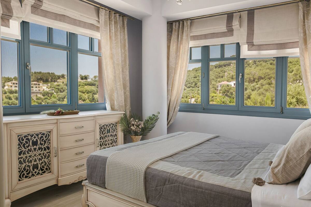 A bedroom with a bed, a dresser, and a window with a view of greenery.