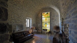 Et rum med stenvægge, et hvælvet loft, et farvet glasvindue, en lædersofa og et mønstret gulv.