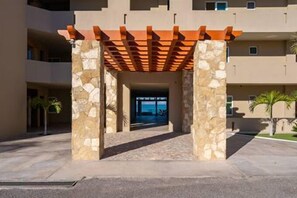 Une entrée d’immeuble avec une arche en pierre et une pergola en bois.
