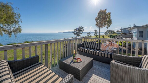 A deck with wicker furniture and a view of the sea.