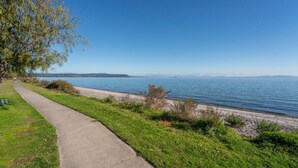 A coastal walkway with a clear view of the sea and distant mountains.