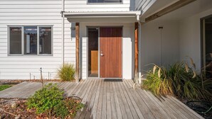 A modern house with a wooden front door, a covered porch, and a wooden deck.