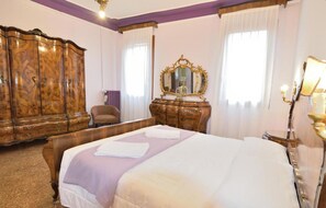 Une chambre d’hôtel avec un grand lit, une armoire en bois, une commode, une chaise et un miroir.