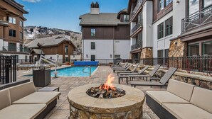 A poolside area with lounge chairs, a fire pit, and a pool. - Slopeside Townhome in Beaver Creek | Chalet Montsor (Beaver Creek)