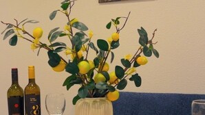 Une table à manger dressée avec des assiettes, des couverts, des bouteilles de vin et un vase rempli de fleurs jaunes.