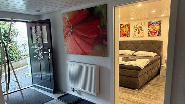 Une chambre moderne avec un grand lit, un radiateur et une porte donnant sur un balcon.