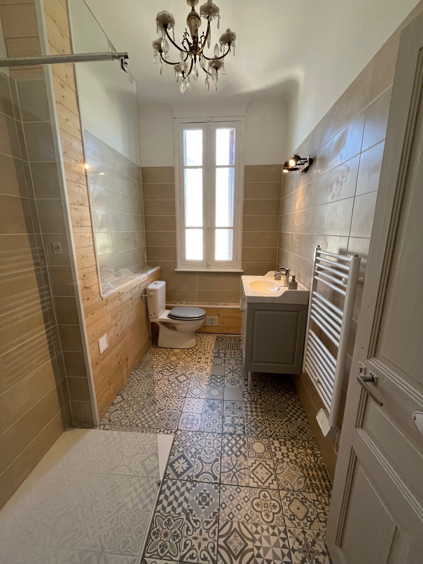 A bathroom with a shower, toilet, sink, and a window.