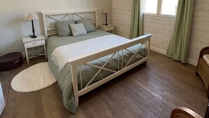 A bedroom with a bed, bedside tables, a lamp, a guitar, and a window with curtains.
