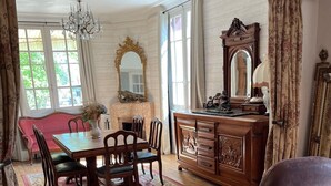 A traditional room with a wooden dining table, chairs, a sofa, and a cabinet with a mirror.