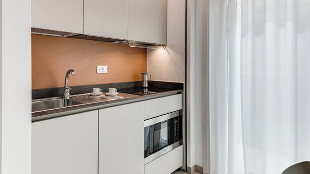 Eine moderne Küche mit weißen Schränken, einer Edelstahl-Spüle und einem Backofen.