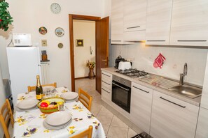 A compact kitchen with a refrigerator, stove, sink, and wooden cabinets. - Rosa House Varenna Apartment with a view of Lake Como (Varenna)