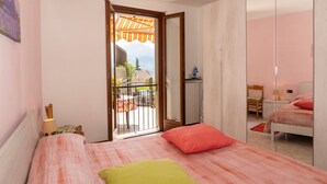 Un dormitorio con cama, mesita de noche, espejo y vistas al exterior.