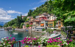A waterfront village with colorful buildings, a boat dock, and lush greenery. - Rosa House Varenna Apartment with a view of Lake Como (Varenna)