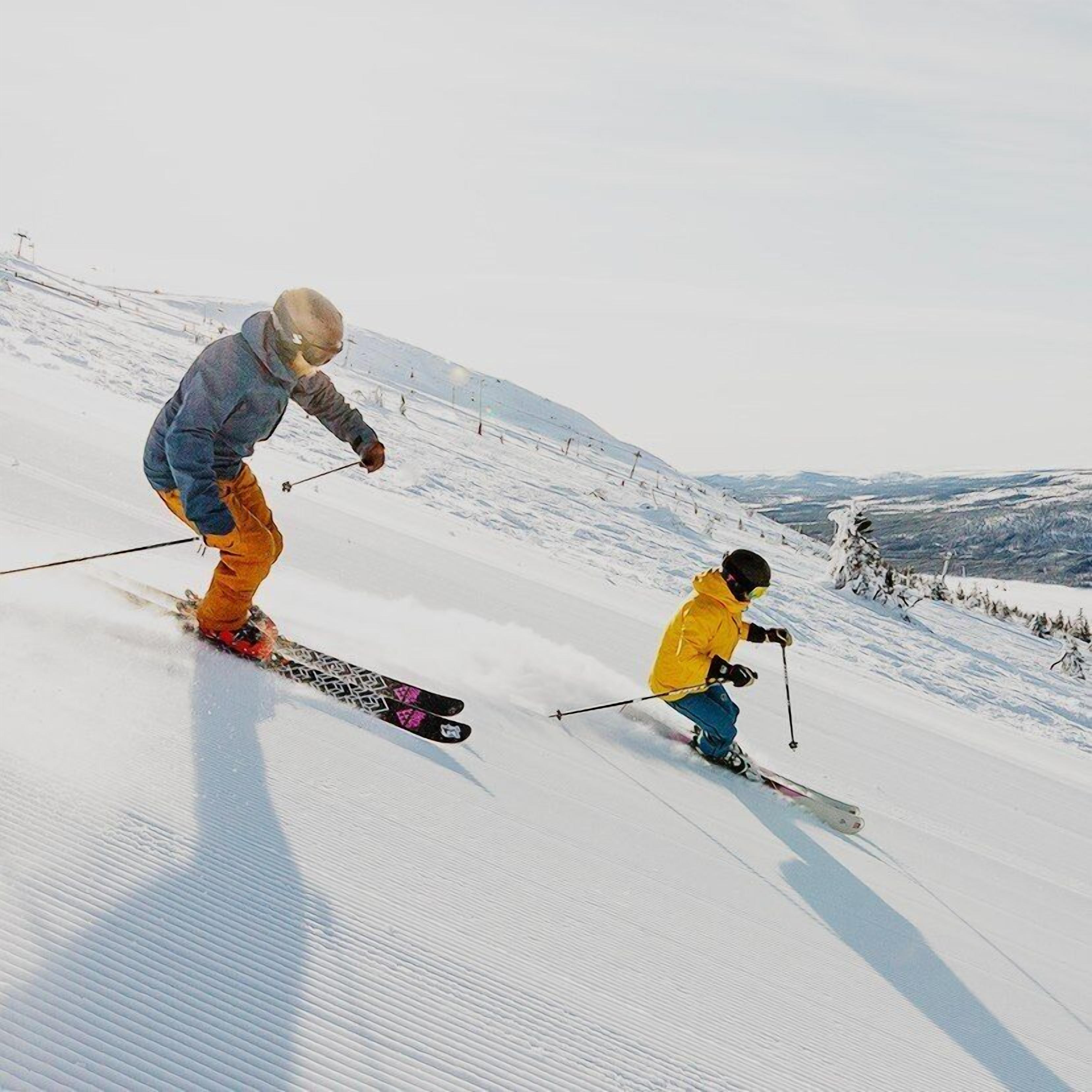 Pista de esqui coberta de neve com dois esquiadores.