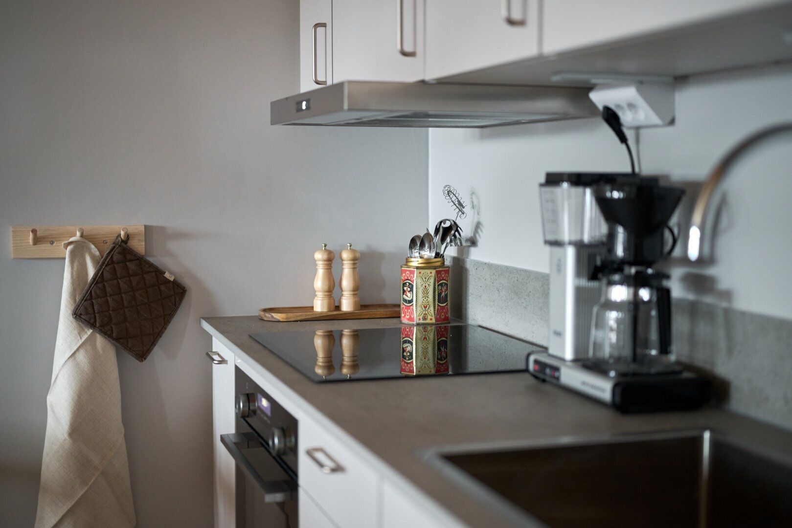 A kitchen with a countertop, a coffee maker, a kettle, and a spice rack.
