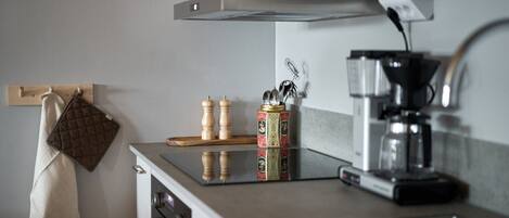 A kitchen with a countertop, a coffee maker, a kettle, and a spice rack.