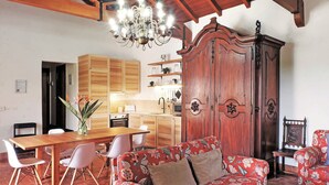 Un comedor con una mesa de madera y sillas blancas, un sofá floral rojo y un mueble de madera grande.