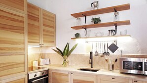 Una cocina moderna con armarios de madera, horno empotrado, microondas y un colgador para utensilios.