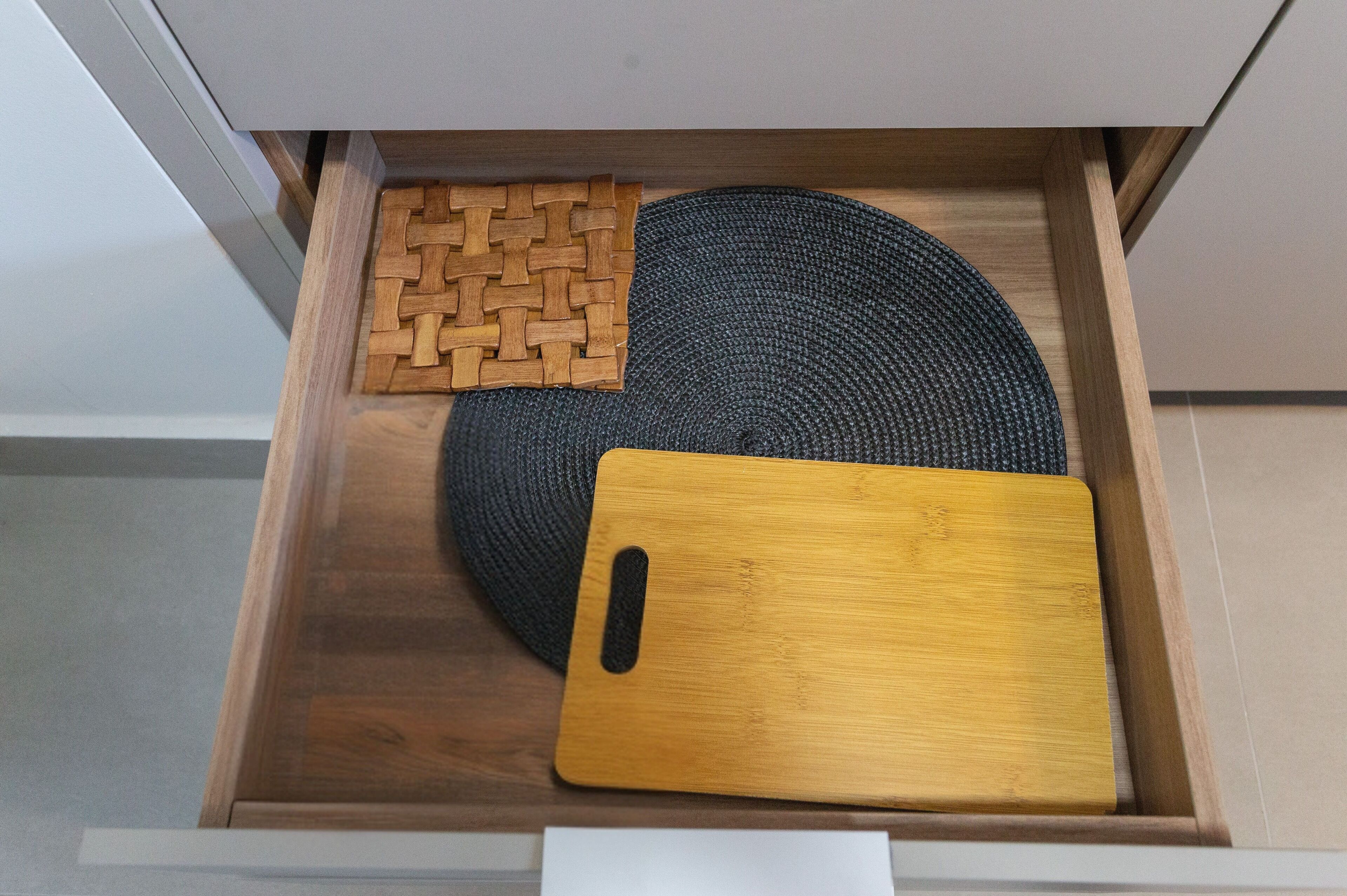 Eine Holzkiste mit einer gewobenen Matte, einem runden Gewebestück und einem Holzschneidebrett.