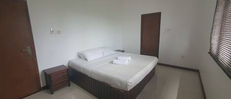 Une chambre à coucher avec un lit, une table de chevet, une armoire en bois et une porte.