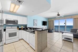 Cocina moderna con una isla central, un área de comedor con sofá y un balcón con vista al océano.