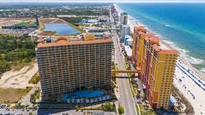 Un hotel costero con varios edificios altos, una playa y un puerto deportivo.