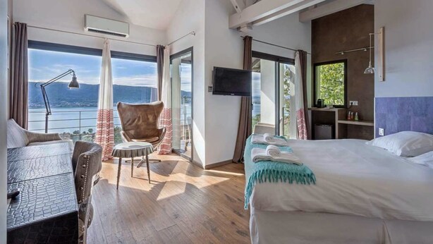 A modern hotel room with a large bed, a desk, a chair, and a TV. - Le Clos du Lac: Villa with lake view (Veyrier-du-Lac)