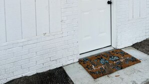 A white door with a keypad lock, a doormat, and a small outdoor light fixture. - Madison gate studio (Goldsboro)