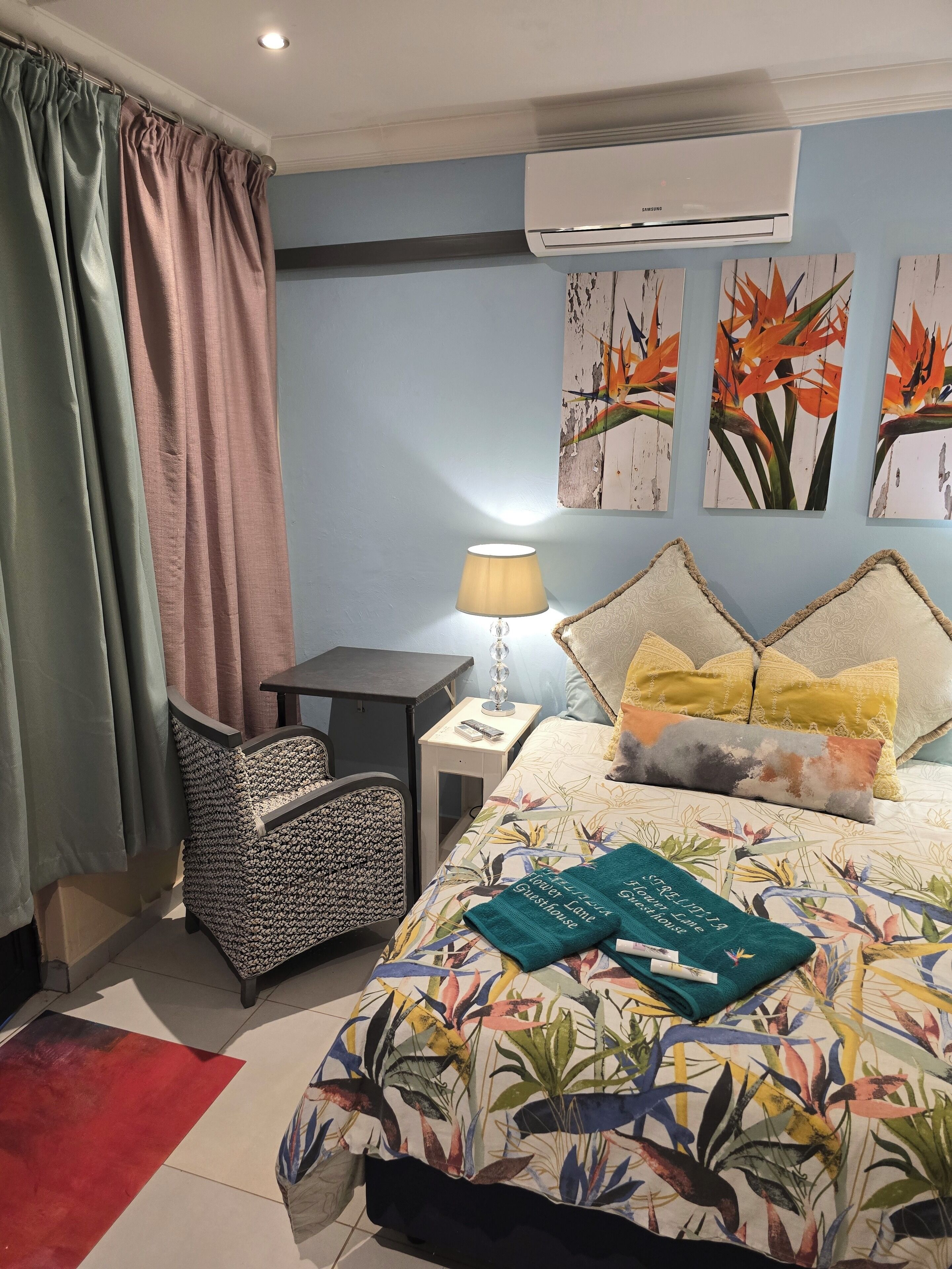 A bedroom with a bed, a chair, a nightstand, and a lamp.
