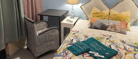 A bedroom with a bed, a chair, a nightstand, and a lamp.
