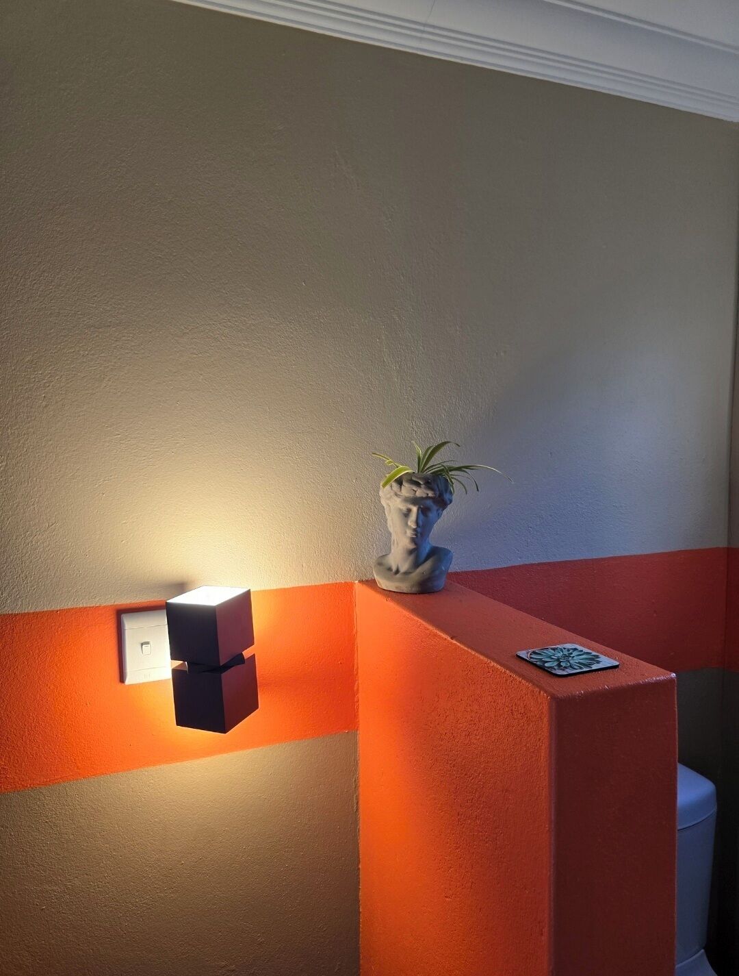 Een receptie met een lamp, een potplant en een rode accentmuur.