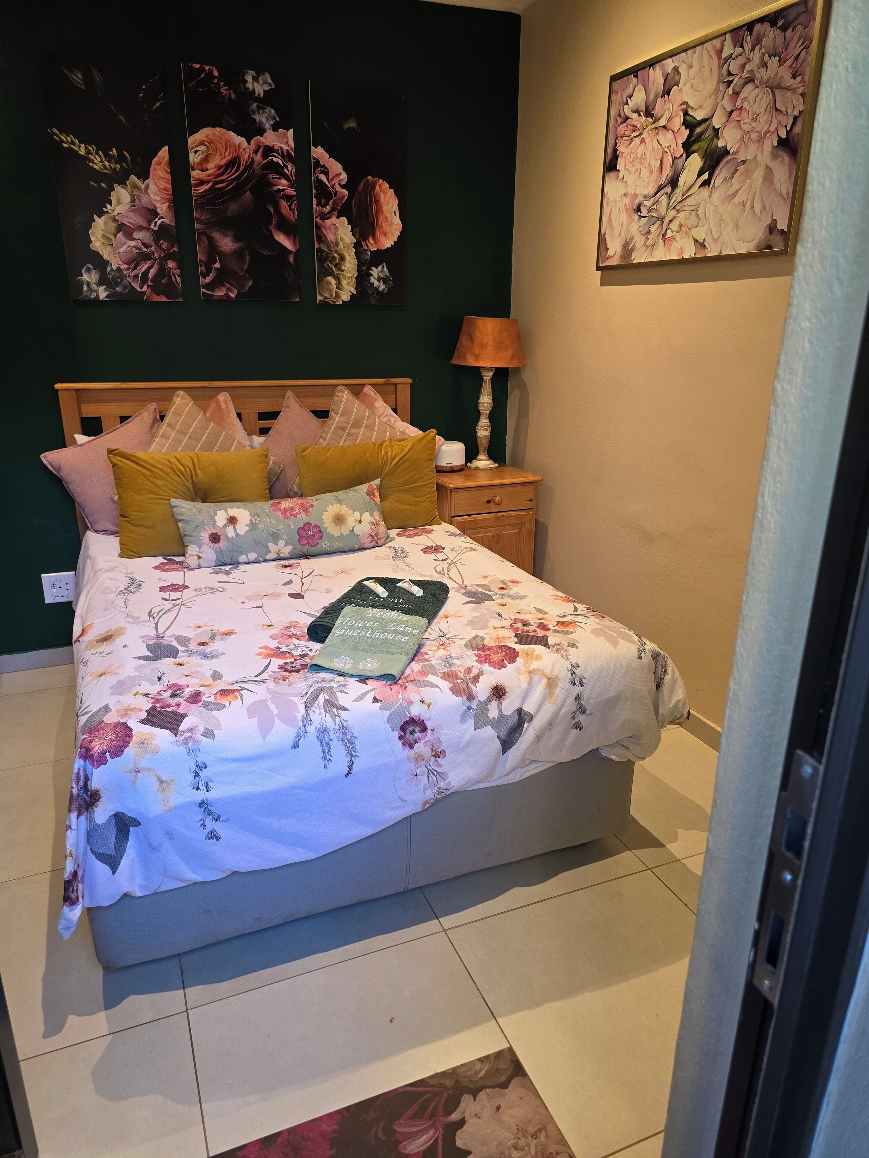A neatly made bed with floral bedding, a wooden headboard, and multiple pillows.