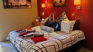 A bedroom with a bed, pillows, and a nightstand. - Flower Lane Guesthouse  (Kathu)
