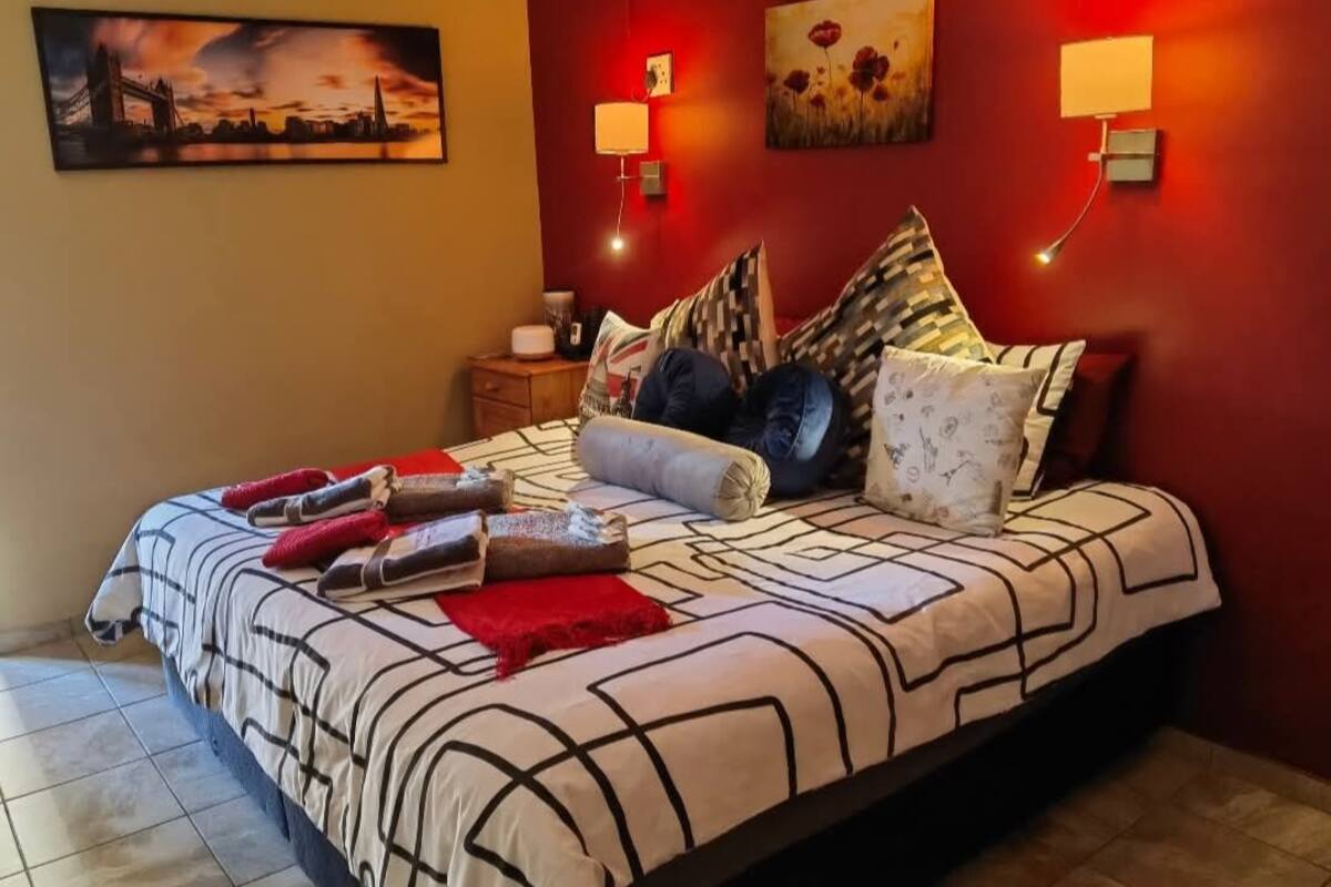 Un dormitorio con cama, almohadas y mesita de noche.