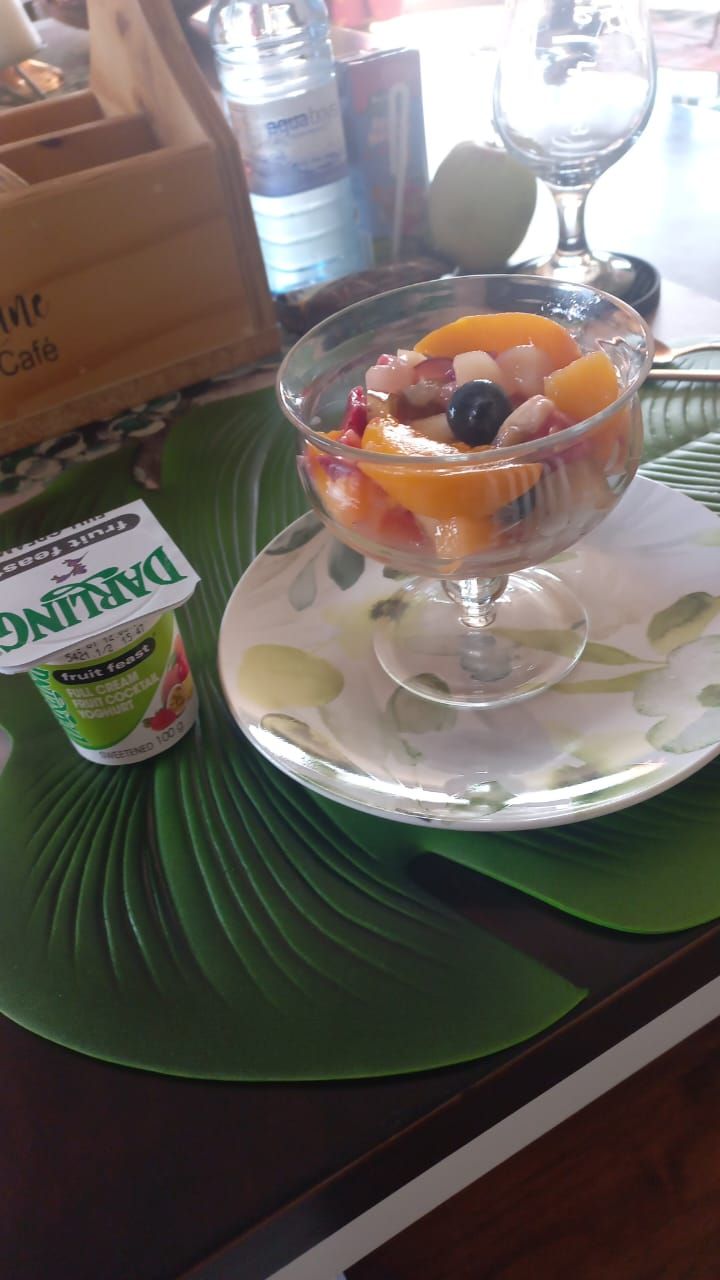 Un parfait aux fruits servi dans un bol en verre, posé sur une assiette agrémentée d’une serviette de table verte.