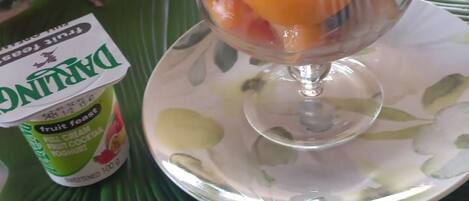 Un parfait aux fruits servi dans un bol en verre, posé sur une assiette agrémentée d’une serviette de table verte.