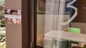 A glass door with a '3' sign, a small table with chairs, and a 'Mind the Step' sign. - Flower Lane Guesthouse  (Kathu)