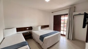 Une chambre d’hôtel avec deux lits, une petite table de chevet avec une lampe, une fenêtre avec des rideaux et une porte donnant sur l’extérieur.