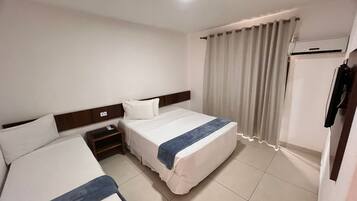 A hotel room with two beds, a nightstand, a wardrobe, and a window with curtains.