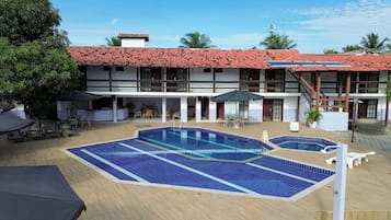 Un hotel con piscina, mobiliario exterior y tejado de tejas rojas.