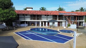 A hotel with a swimming pool, outdoor seating, and a red-tiled roof. - Rede Andrade Estrela Dalva Praia (Porto Seguro)