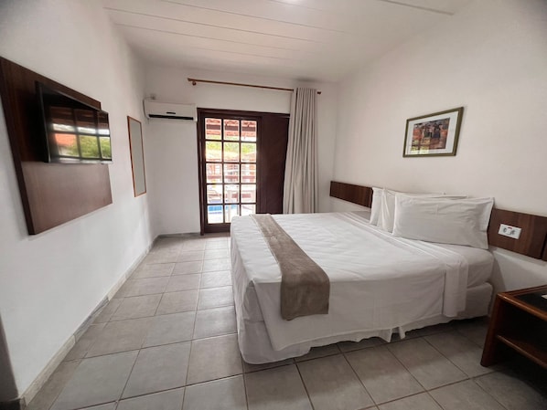 A hotel room with a bed, a TV, a window, and a door. - Rede Andrade Estrela Dalva Praia (Porto Seguro)