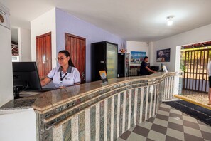 Un comptoir d’accueil avec un ordinateur, un réfrigérateur et une porte en arrière-plan.