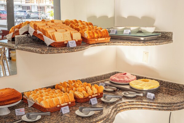A buffet setup with various bread options and a meat dish.