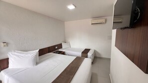Une chambre d’hôtel avec deux lits, une tête de lit en bois, une table de chevet, un climatiseur mural et un téléviseur.
