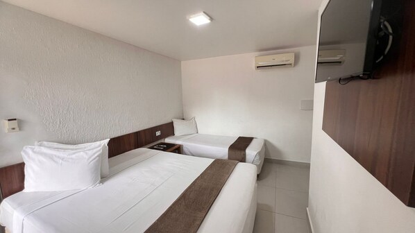 Une chambre d’hôtel avec deux lits, une tête de lit en bois, une table de chevet, un climatiseur mural et un téléviseur.