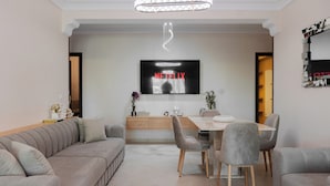 Un salon moderne comprenant un coin repas, un téléviseur à écran plat fixé au mur et un aménagement de style minimaliste.