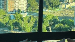 Une pièce dotée d’une grande fenêtre donnant sur un paysage urbain avec des immeubles et des arbres.