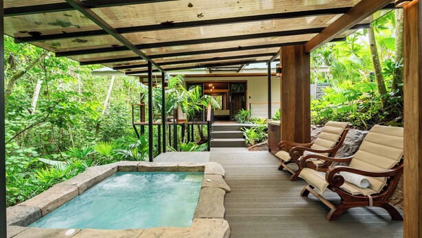 A covered outdoor area with a hot tub, wooden deck, and lounge chairs. - Secret Bungalows Lechu (Penas Blancas)